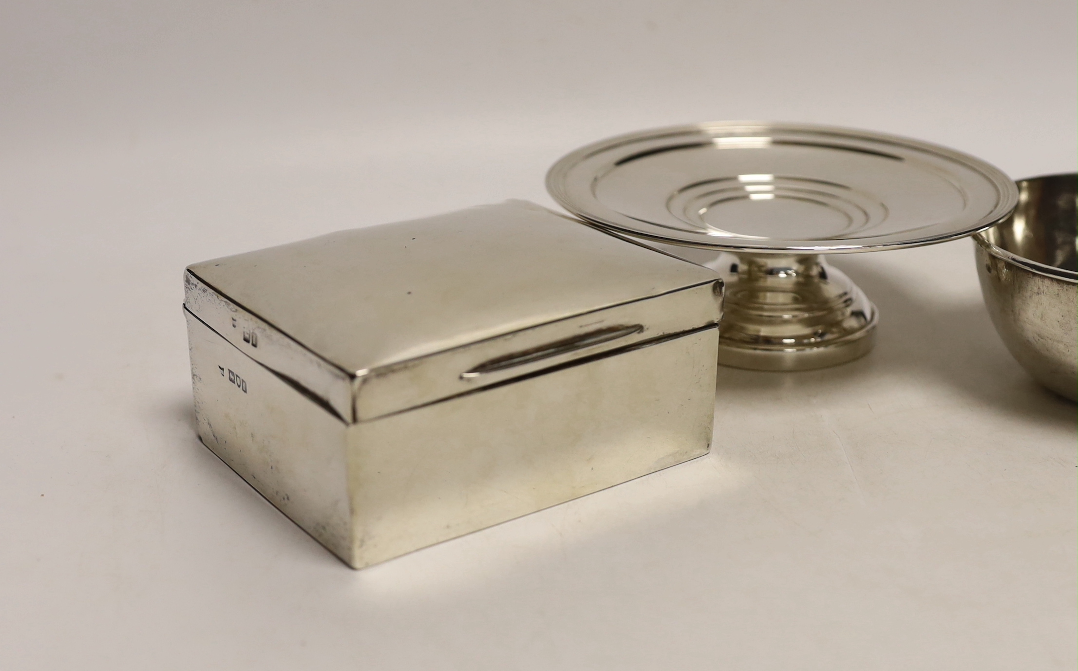 An Edwardian silver mounted cigarette box, London, 1901, 10.8cm, a small silver tazza and two continental white metal bowls, with inset coin bases.